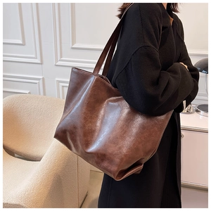Vue latérale d'un grand sac cabas en simili cuir marron porté par un mannequin en studio