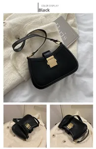 Detail view of black vintage leather underarm bag with elegant gold buckle and strap