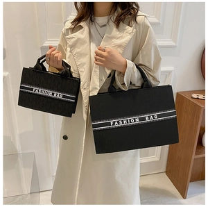 Détail de cabas en toile noire en deux tailles avec lettrage blanc rayé fashion bag