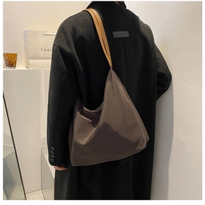 Détail du sac cabas en nylon chocolat souple avec anses en cuir marron et texture drapée