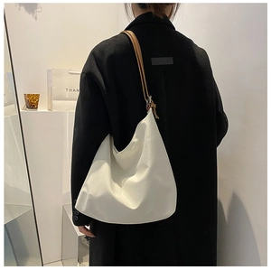 Sac hobo beige minimaliste avec bandoulière marron porté par un mannequin en intérieur doux