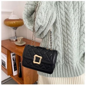 Detail of classic black quilted shoulder bag with gold square lock on a stylish woman