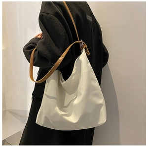 Détail du sac fourre-tout crème avec bandoulières en cuir marron porté à l'épaule
