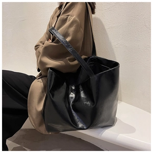 Détails du grand sac cabas noir brillant montrant la texture souple et les plis