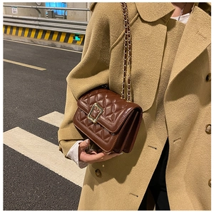 Detail of a dark brown quilted shoulder bag with gold hardware and chain strap