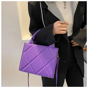 Close-up of a stylish purple quilted crossbody bag with golden metal hardware detail