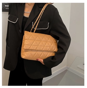 Détail d'un sac cabas en similicuir matelassé marron clair avec chaîne dorée