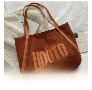Macro shot of faux suede tote bag with HOOTO embroidery and spacious internal compartment