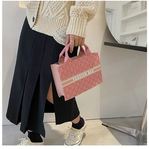 Gros plan détaillé d'un sac cabas rose en toile avec imprimés M et motif à rayures
