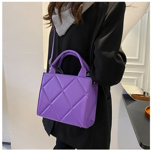 Purple quilted crossbody bag with diamond stitching shown on a person in a modern blazer