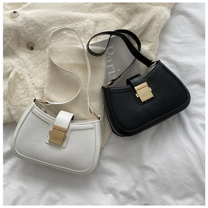 Detail of white and black PU leather underarm bags with gold rectangular metal buckles