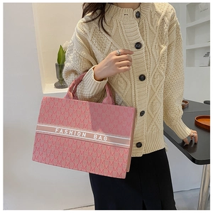 Détail du sac cabas en toile rose avec jacquard à motif M et bande logo blanche