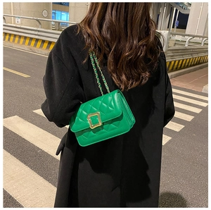 Close-up of green quilted shoulder bag with large gold buckle and leather chain strap