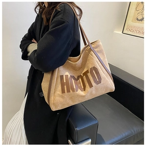 Detail of dark khaki suede tote bag with 3D HUYTO letter patch and brown leather straps