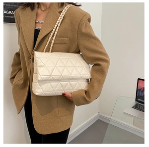 Détail d'un sac à main blanc en similicuir matelassé avec bandoulière en chaîne dorée