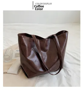 Détail du grand sac cabas marron café en similicuir brillant sur tissu blanc