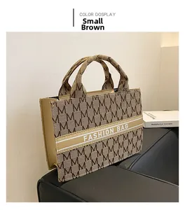 Vue détaillée du sac cabas en toile marron avec imprimé lettre sur canapé cuir