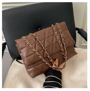 Détail du sac matelassé marron foncé avec chaîne dorée sur un tissu en laine blanche
