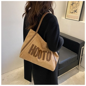 Detail view of khaki suede tote bag with brown HOOTO lettering and slim leather shoulder strap