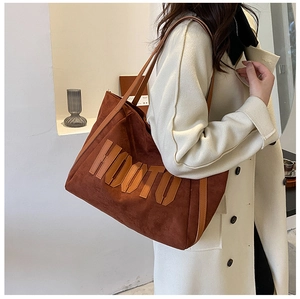 Close-up of brown suede tote bag featuring HOOTO embroidered text and retro aesthetic