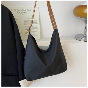 Détail du sac hobo en nylon noir minimaliste avec bandoulières marron contrastées