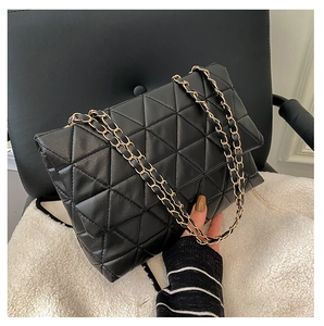 Détail du sac à bandoulière en cuir noir avec matelassage triangulaire et chaîne dorée