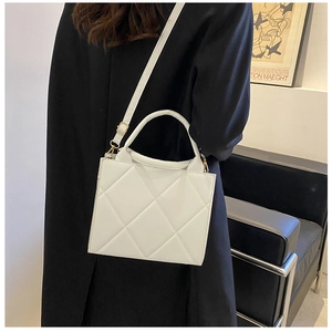 Detailed close-up of a white quilted crossbody bag with golden hardware and leather texture