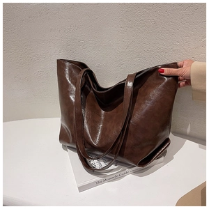 Détail macro du cuir ciré marron foncé sur un grand sac cabas au design minimaliste