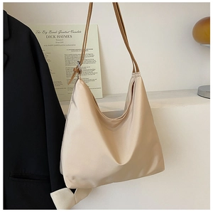 Détail du sac bandoulière en satin champagne avec boucle métal et anses brunes