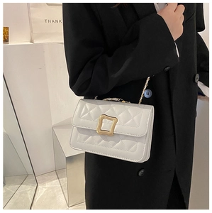 Close-up of a white quilted crossbody bag with a gold buckle and metal chain strap