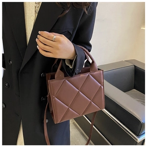 Detail of brown quilted leather crossbody bag with rhombic stitching and top handle
