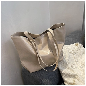 Détail du grand sac cabas beige en cuir sur un canapé avec gilet en maille blanc