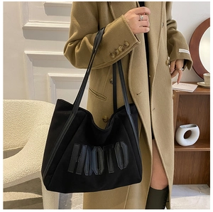 Close-up of black tote bag featuring embossed HMOTU lettering and durable shoulder straps