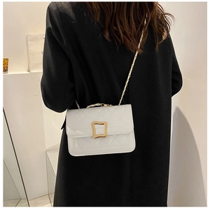 Detail of white quilted crossbody bag with golden metal buckle on black coat