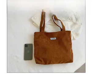 Gros plan d'un sac cabas en velours côtelé marron avec étiquette sur tissu blanc