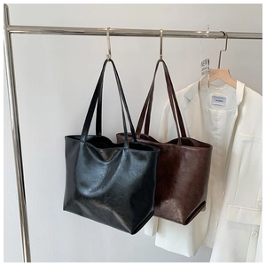 Détail de sacs cabas vintage en noir et marron café sur des cintres minimalistes