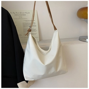 Détail du sac à bandoulière hobo blanc crème minimaliste avec de fines anses en cuir marron