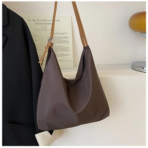 Détail du sac hobo en nylon marron foncé avec une bandoulière à nœud décoratif