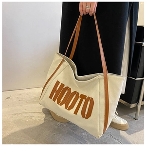 Detail of the suede tote bag showing contrast leather straps and HOOTO letter patch