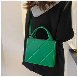 Close-up of bright green quilted square bag with gold hardware and top handle detail