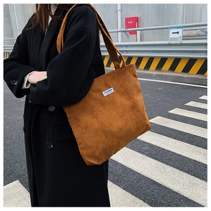 Gros plan du sac cabas en velours côtelé marron avec étiquette blanche FASHION brodée