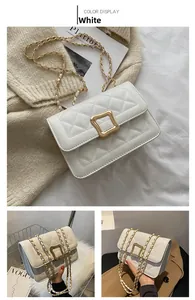Detail of white quilted crossbody bag with golden square lock and chain strap
