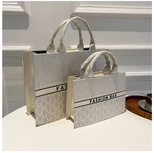 Détail de sacs fourre-tout en toile beige avec motif M et ruban Fashion Bag élégant