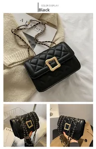 Close-up of black quilted leather texture and gold metal buckle on small square bag