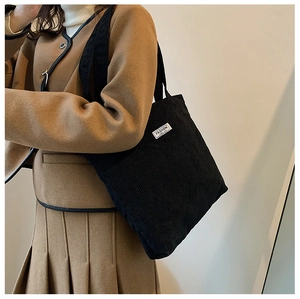 Détail d'un sac cabas en velours côtelé noir avec étiquette de mode en situation