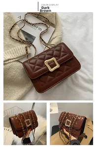 Detail of dark brown quilted crossbody bag with gold square clasp and chain strap
