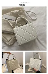 Macro shot of white quilted rhombic texture and gold metal clasp on a small square bag