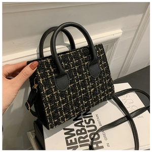 Dettaglio della borsa tote in tweed nero e oro con manici in ecopelle e ganci metallici oro
