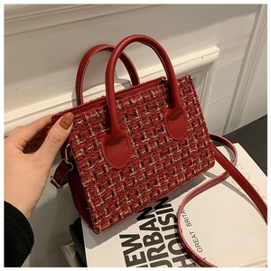 Dettaglio della borsa in tweed rosso con trama dorata, doppi manici e tracolla