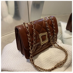 Detailed macro of vintage brown quilted leather bag featuring a gold square metallic clasp